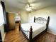 Bedroom featuring ceiling fan, wood floor, mirrored closet, and large window with curtains allowing natural light at 10726 W Kelso Dr, Sun City, AZ 85351