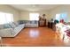Spacious living room featuring wood floors, a comfortable sofa, and natural light from three windows at 10726 W Kelso Dr, Sun City, AZ 85351