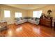 Bright living room with a comfortable sectional sofa, wood floors, and three windows allowing lots of natural light at 10726 W Kelso Dr, Sun City, AZ 85351