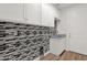 Modern laundry room showcasing mosaic backsplash and cabinets, along with a sink and a doorway at 1336 E Belmont Ave, Phoenix, AZ 85020