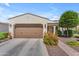 Charming home with a two-car garage, desert landscaping, and a tile roof under a blue sky at 14200 W Village Pkwy # 2128, Litchfield Park, AZ 85340