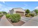 Home featuring a two-car garage, desert landscaping, and a concrete driveway on a sunny day at 14200 W Village Pkwy # 2128, Litchfield Park, AZ 85340