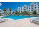 Resort-style swimming pool surrounded by lounge chairs and palm trees, with luxury apartments in the background at 2511 W Queen Creek Rd # 325, Chandler, AZ 85248