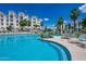 Beautiful swimming pool with sun loungers, landscaping, and multi-story apartments with blue awnings in the background at 2511 W Queen Creek Rd # 325, Chandler, AZ 85248