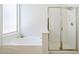 Bright bathroom featuring a soaking tub, a glass-enclosed shower, and a window at 2755 N 103Rd Ave, Avondale, AZ 85392
