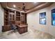Home office with a wooden desk, built-in shelves, and a ceiling fan at 31721 N 138Th Pl, Scottsdale, AZ 85262