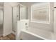 Bright bathroom showcases a bathtub and shower combination with window at 41251 W Cahill Dr, Maricopa, AZ 85138
