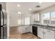 Open kitchen featuring white cabinets, gray countertops, a black refrigerator, and wood-look floors at 41251 W Cahill Dr, Maricopa, AZ 85138