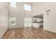 Open-concept living room featuring wood flooring and a large window with views of the backyard at 41251 W Cahill Dr, Maricopa, AZ 85138