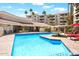 Community swimming pool with lounging chairs and red umbrellas at 4200 N Miller Rd # 408, Scottsdale, AZ 85251