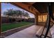 Covered patio with swing overlooks a spacious, well-maintained backyard featuring lush green grass and mature trees at 5016 S Curie Way, Mesa, AZ 85212