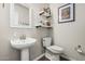 The powder bathroom showcases a pedestal sink, toilet, and decorative wall shelves and art at 5437 W Red Bird Rd, Phoenix, AZ 85083