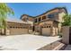 Beige stucco two-story home featuring an arched entryway, desert landscaping, and a 3-car garage with ample parking at 5437 W Red Bird Rd, Phoenix, AZ 85083