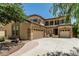 Beige stucco two-story home featuring an arched entryway, desert landscaping, and a 3-car garage with ample parking at 5437 W Red Bird Rd, Phoenix, AZ 85083