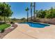 Backyard pool featuring a rock waterfall, tall palm trees, and a manicured landscape for resort-style living at 5437 W Red Bird Rd, Phoenix, AZ 85083