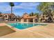 Community pool featuring a covered seating area, palm tree, and well-maintained landscaping against a blue sky backdrop at 609 E Mesquite Cir # D132, Tempe, AZ 85288