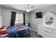 Cozy bedroom with a ceiling fan, large window, and white dresser with a round decorative mirror at 6605 W Altadena Ave, Glendale, AZ 85304