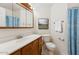 Bright bathroom features a vanity with framed mirror, a toilet and blue striped shower curtain at 6719 W Sack Dr, Glendale, AZ 85308