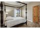 This primary bedroom is bathed in natural light with a ceiling fan, wood door, and a charming four-poster bed at 6861 W Calle Lejos --, Peoria, AZ 85383