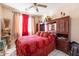 Comfortable bedroom features a bed with red bedding and a ceiling fan at 7102 W Pueblo Ave, Phoenix, AZ 85043