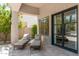 Cozy covered patio with tiled floors, lounge chairs, and a black-framed glass door leading inside at 7710 E Tardes Dr, Scottsdale, AZ 85255