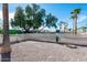 Fenced community dog park featuring lush trees, gravel ground cover, and convenient waste disposal stations at 7807 E Main St # E2, Mesa, AZ 85207