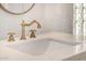 Close up of the bathroom sink with the brass faucet and white quartz countertop at 9112 E Palm Tree Dr, Scottsdale, AZ 85255
