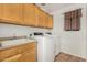 Laundry room with wooden cabinets, sink, countertop, and white washer and dryer units at 9350 W Williams St, Tolleson, AZ 85353