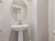 This powder room features a pedestal sink, round mirror, and neutral colors at 9412 E Sequence Ave, Mesa, AZ 85212