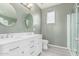 Modern bathroom featuring double sink vanity, oval mirrors, and glass-enclosed shower at 11836 W Planada Ct, Sun City, AZ 85373