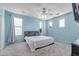 Light-filled bedroom with blue walls, plush carpet, and a ceiling fan at 11836 W Planada Ct, Sun City, AZ 85373