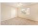 Bright bedroom with neutral walls, carpet, ceiling fan, and a large window overlooking the yard at 15440 W Mauna Loa Ln, Surprise, AZ 85379