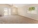 Bright, carpeted living room with sliding glass door, ceiling fan, and natural light at 15440 W Mauna Loa Ln, Surprise, AZ 85379