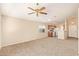 Open-concept living area with neutral carpeting, ceiling fan, and access to the kitchen at 15440 W Mauna Loa Ln, Surprise, AZ 85379