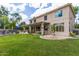 Lush backyard with green grass, covered patio, outdoor seating, and mature trees at 1571 E Saratoga Ct, Gilbert, AZ 85296