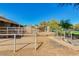 Wide view of horse barn with gated paddocks and a horse in the distance, with trees and green space at 1571 E Saratoga Ct, Gilbert, AZ 85296