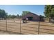 View of horse barn with two horses in a gated enclosure surrounded by mature landscaping under a clear sky at 1571 E Saratoga Ct, Gilbert, AZ 85296