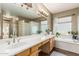 A large bathroom featuring a dual sink vanity, jacuzzi tub, and decorative glass block shower at 1571 E Saratoga Ct, Gilbert, AZ 85296