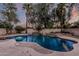 Serene backyard pool with ambient lighting, tropical landscaping, and a custom rock waterfall feature at 1571 E Saratoga Ct, Gilbert, AZ 85296