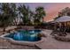 Inviting pool with rock features, baja step, and a fire pit in a beautifully landscaped backyard at 1571 E Saratoga Ct, Gilbert, AZ 85296
