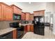 Well-equipped kitchen featuring dark wood cabinetry, granite countertops, and sleek black appliances, offering style and functionality at 1630 W Calle Del Norte --, Chandler, AZ 85224