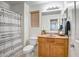 Well-lit bathroom with a shower featuring a decorative curtain, wooden vanity, and neutral-toned walls at 17802 N 114Th Ln, Surprise, AZ 85378