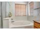 Bathroom featuring a soaking tub with white surround, a window with blinds, and neutral finishes at 17802 N 114Th Ln, Surprise, AZ 85378