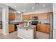 Modern kitchen with oak cabinets, black appliances, a breakfast bar, and pendant lighting at 17802 N 114Th Ln, Surprise, AZ 85378