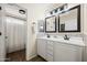 Bathroom features a double vanity, decorative mirrors and lighting, and a shower with curtain at 18030 W Caribbean Ln, Surprise, AZ 85388