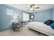 Blue bedroom features a ceiling fan, desk, neutral carpet, and window to let in natural light at 18030 W Caribbean Ln, Surprise, AZ 85388