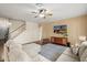 Bright living room with cozy sectional sofa, ceiling fan, modern decor, and staircase access to the upper level at 18030 W Caribbean Ln, Surprise, AZ 85388