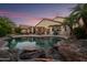 Inviting backyard oasis with a private pool, covered patio, and lush tropical landscaping at 18030 W Caribbean Ln, Surprise, AZ 85388