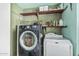 A practical laundry room equipped with a front-load washer, a dryer, and shelving at 19302 W Melvin St, Buckeye, AZ 85326