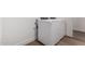 A well lit laundry room featuring modern, white, stacked washer and dryer units and light wood-look flooring at 19338 S 212Th Pl, Queen Creek, AZ 85142